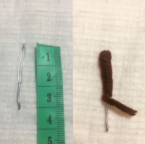 Small brown crochet amigurumi deer leg with metal wire next to green measuring tape showing 4 cm length.
