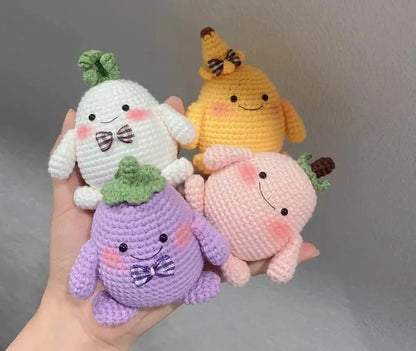 Set of four colorful amigurumi plush animals featuring a white bunny, yellow chick, purple eggplant, and pink pig with.