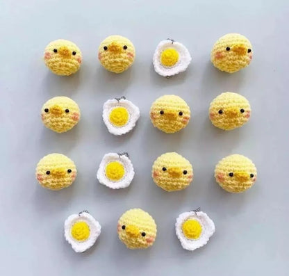 Yellow crocheted amigurumi chicks and white amigurumi fried eggs arranged in a grid on a light background.
