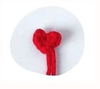 White round amigurumi with red crochet heart and stem detail on front.