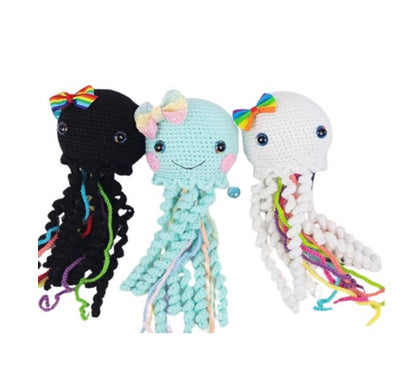 Set of three whimsical crochet amigurumi jellyfish with colorful tentacles and bows in black, light blue, and white designs.