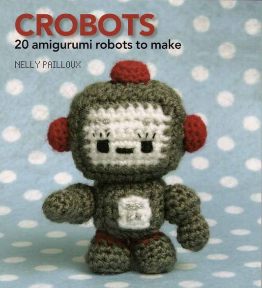 Crochet amigurumi robot with green body, red ear details, and square face on blue polka dot background.
