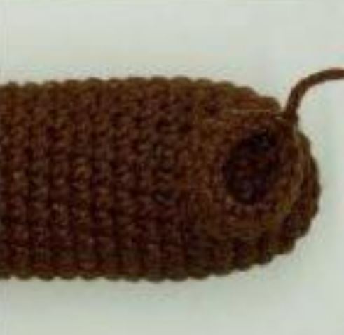 Brown crochet dachshund amigurumi body piece with a small tail loop.