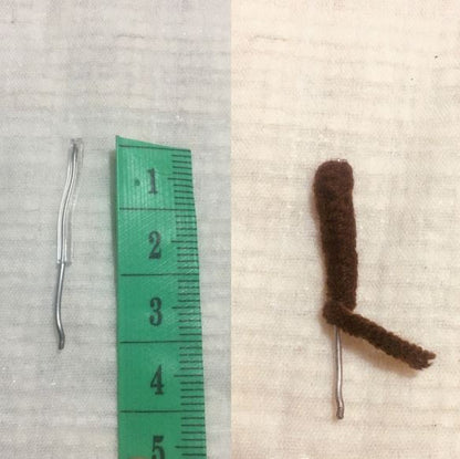 Small brown crochet amigurumi deer leg with metal wire next to green measuring tape showing 4 cm length.