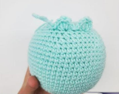 Handheld light turquoise crochet amigurumi ball with subtle textured loops on top.